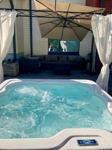 vasca idromassaggio con ombrellone in cortile di Cozy Holiday Home with Outside Jacuzzi a Espoo