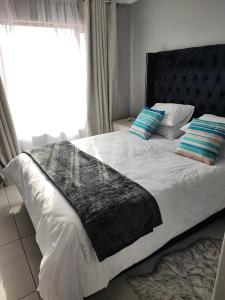 a bed with a black and white blanket and a window at Kyalami Boulevard Estate, Kyalami Hills ext 10 Robin Road Midrand in Midrand