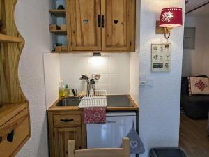 Elle comprend une petite cuisine avec des placards en bois et un évier. dans l'établissement studio terrasse de charme près des pistes, à Bernex