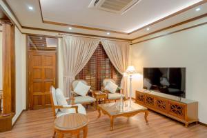 un soggiorno con TV, tavolo e sedie di Alafehi Retreat a Fuvahmulah