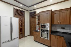 una cucina con armadi in legno e frigorifero bianco di Alafehi Retreat a Fuvahmulah