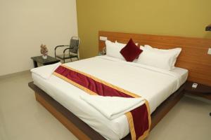 ein Schlafzimmer mit einem großen Bett mit weißer Bettwäsche und roten Kissen in der Unterkunft Hotel Shri Durga International in Bangalore