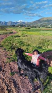 a little girl and a black dog on a dirt road at Weninger Lodge in Urubamba