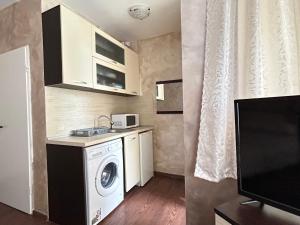 eine kleine Küche mit einer Waschmaschine und einer Mikrowelle in der Unterkunft North Beach Apartments in Primorsko
