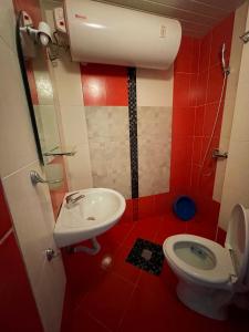 Baño rojo con aseo y lavamanos en North Beach Apartments, en Primorsko