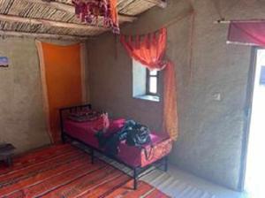 ein rotes Bett in einem Zimmer mit Fenster in der Unterkunft Karawanserail-Khamlia in Khamliya