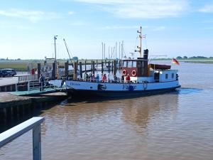 un barco atracado en un muelle con gente en él en Ediths Haus, en Rhauderfehn