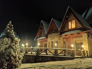 een huis in de sneeuw met een kerstboom bij Садиба "Коренюки" in Tatariv