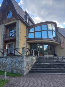 a house with a stone staircase in front of it at Садиба "Коренюки" in Tatariv