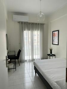 a white bedroom with a bed and a chair at Mary Lo Guest House in Nydri