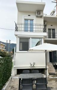 a white house with a table and an umbrella at Mary Lo Guest House in Nydri