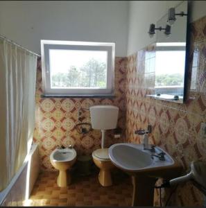 a bathroom with a sink and a toilet and a window at Casa Do Bosque in Nadadouro