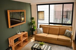 ein Wohnzimmer mit einem Sofa und einem Spiegel in der Unterkunft Moderno Departamento con terraza pegado a la condesa in Mexiko-Stadt