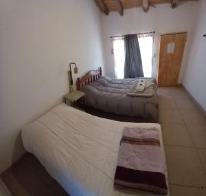 um quarto com 2 camas e uma janela em La Haciendita Hostel em Humahuaca