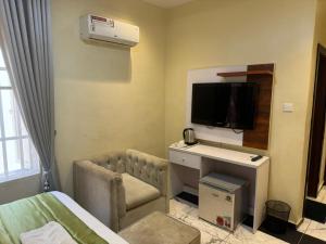 um quarto de hotel com uma secretária e uma televisão em Sugarland Hotel and Suite em Ikeja