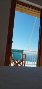 a bedroom with a bed and a balcony with a chair at FAROS in Agios Nikolaos