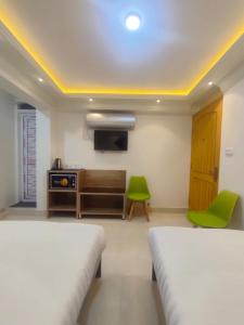 2 łóżka w pokoju z telewizorem i krzesłem w obiekcie White Hotel w Kwecie