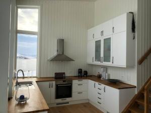 a kitchen with white cabinets and a sink and a window at Unique panorama - Senja in Finnsæter