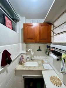 uma pequena cozinha com um lavatório e armários de madeira em Studio no Largo da Carioca - Rio de Janeiro no Rio de Janeiro