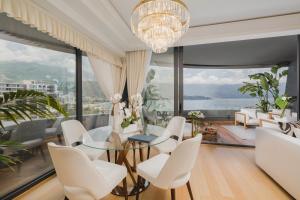 a dining room with a glass table and white chairs at Vissi d'Arte Serviced Apartments in Budva