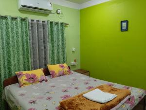 Bett in einem Zimmer mit grünen Wänden in der Unterkunft Anjali HOMESTAY in Shiliguri