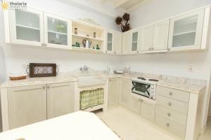 a white kitchen with white cabinets and a sink at Tholaria Boutique Hotel in Astypalaia