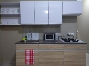 cocina con armarios blancos, fregadero y microondas en Milestone City - Appartements à louer en Antananarivo