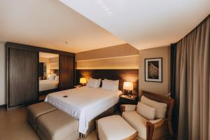 um quarto de hotel com uma cama e duas cadeiras em Golden Tulip Natal Ponta Negra em Natal
