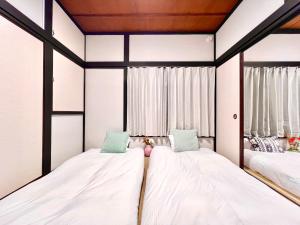 two beds in a room with two windows at AX-Ojima House in Tokyo