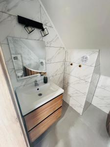 uma casa de banho branca com um lavatório e um espelho em Domki i Apartamenty Wypoczynkowe Lidzbark em Lidzbark