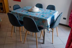 une table avec des chaises et un chiffon de table bleu avec un chapeau dans l'établissement CasaFrancesca Calasetta, à Calasetta