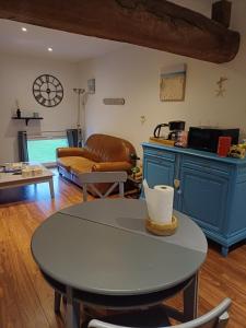 uma sala de estar com uma mesa e um sofá em La Grange des Roisnes em Longué