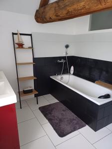 uma casa de banho com uma banheira a preto e branco em La Grange des Roisnes em Longué