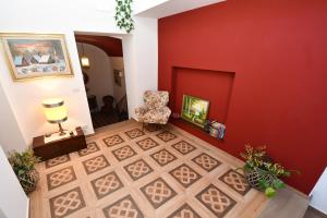 a living room with a red wall and a chair at Al Palazzo in Piazza Armerina
