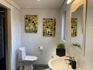 a bathroom with a sink and a toilet and three paintings at Villa Mustalahti in Mikkeli