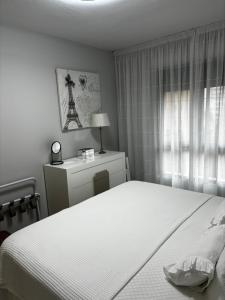 ein Schlafzimmer mit einem weißen Bett und einem Fenster in der Unterkunft Apartamento Bajondillo Playa y piscina in Torremolinos