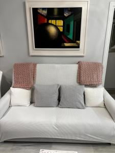 eine weiße Couch in einem Wohnzimmer mit einem Bild an der Wand in der Unterkunft Apartamento Bajondillo Playa y piscina in Torremolinos