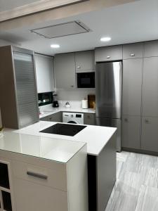 eine Küche mit weißen Arbeitsflächen und Küchengeräten aus Edelstahl in der Unterkunft Apartamento Bajondillo Playa y piscina in Torremolinos