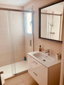 een badkamer met een wastafel en een douche met een spiegel bij Apartamento Las Rotas in Denia