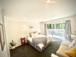a white bedroom with a bed and a balcony at 2 Mile Bay Guesthouse in Taupo