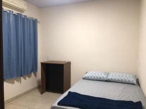 a bedroom with a bed and a blue curtain at Wm Milão in Sinop