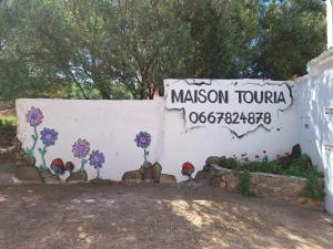um sinal com flores pintadas ao lado de uma parede em Maison Touria em Ouzoud