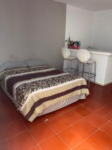 a bedroom with a bed and two chairs at Apartamentos Cupules in Mérida