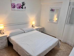 a white bedroom with a bed and two lamps at Plaza Sainetero Arniches in Valencia