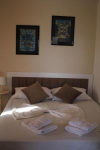 a bed with two towels and two pictures on the wall at Osmenaj Studios in Vlorë