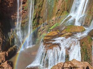 a waterfall with a rainbow in a canyon at Maison Touria in Ouzoud