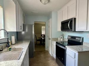 uma cozinha com armários brancos e um aparelho preto em Cottage Hill Comfort em Mobile