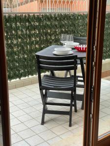a black table and chair with plates and wine glasses at Casa Nives in Sottomarina