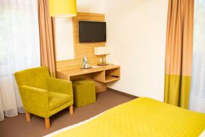 a hotel room with a bed and a chair and a television at Altes Kurhaus Landhotel in Trabelsdorf