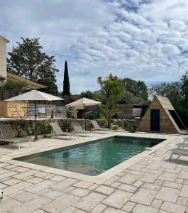 a swimming pool with chairs and umbrellas on a patio at La maison d'HamiH "Gîte et Chambres d'hôtes in Uzès